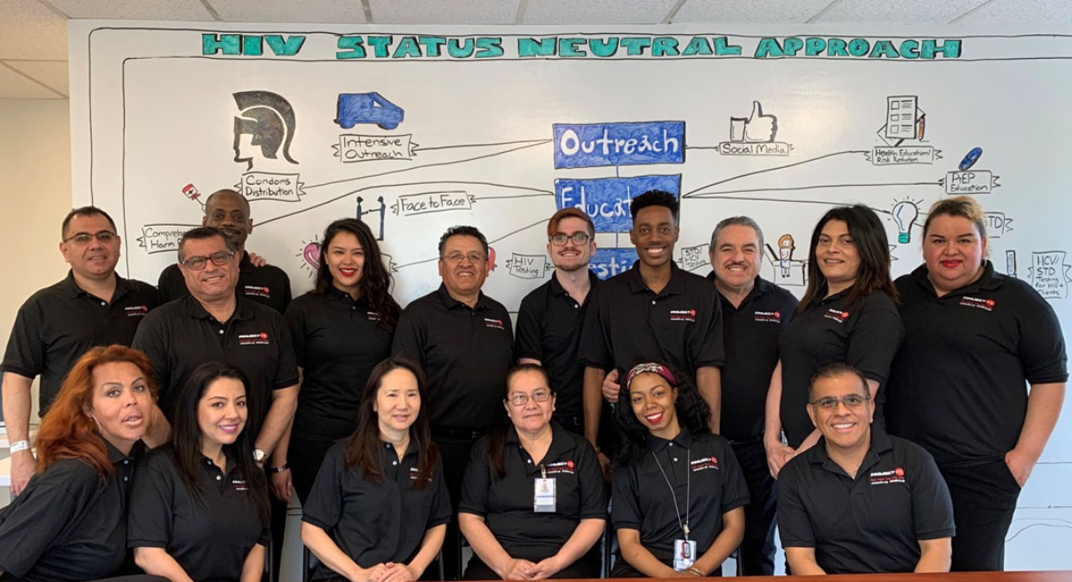 Group photo in front of HIV Status Neutral Approach whiteboard